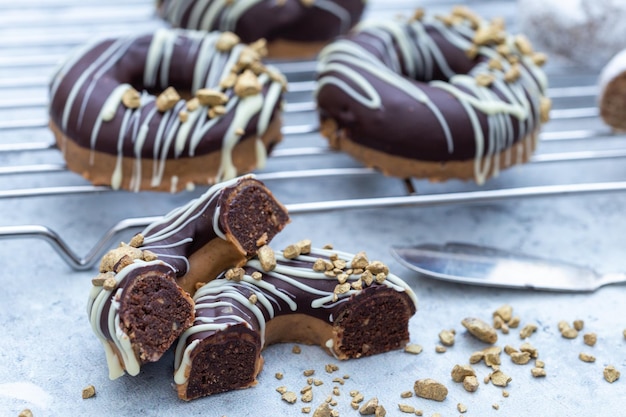 Nahaufnahme eines halbierten, appetitlichen, mit Schokolade überzogenen, rohen Donuts mit Nussstreuseln