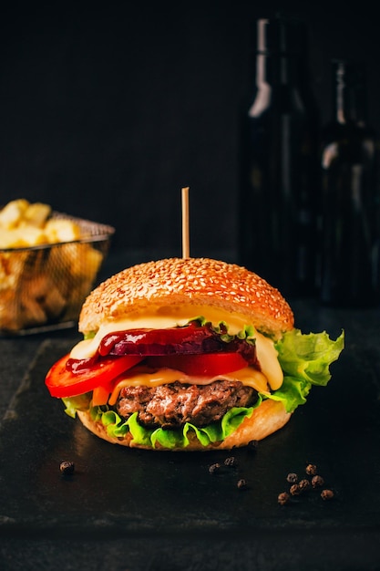 Nahaufnahme eines Hamburgers auf einem schwarzen Tisch mit Pommes Frites im Hintergrund