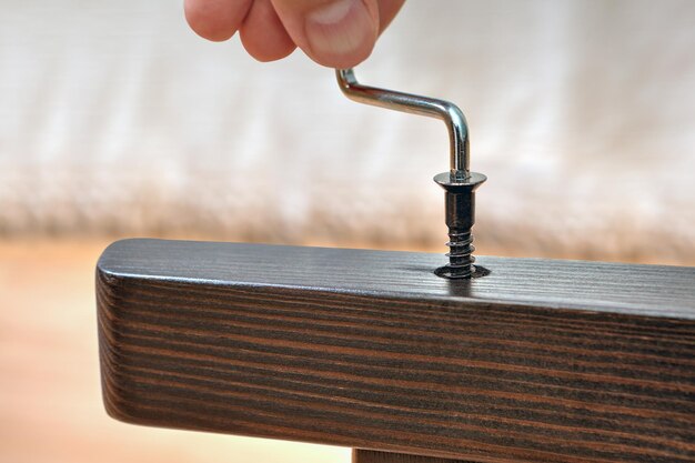 Foto nahaufnahme eines handgeschnittenen reparaturstuhls mit hex-schlüssel und schraube zu hause