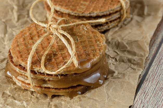 Nahaufnahme eines Haufens Stroopwafel auf braunem Papier mit geschmolzenem Glukosesirup.