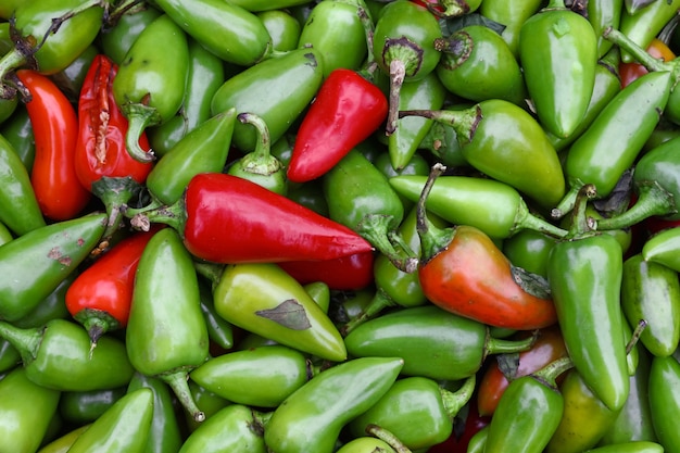 Nahaufnahme eines Haufens vieler frischer grüner und roter scharfer Jalapeno-Chilischoten im Einzelhandel auf dem Bauernmarkt, erhöhte Draufsicht, direkt darüber