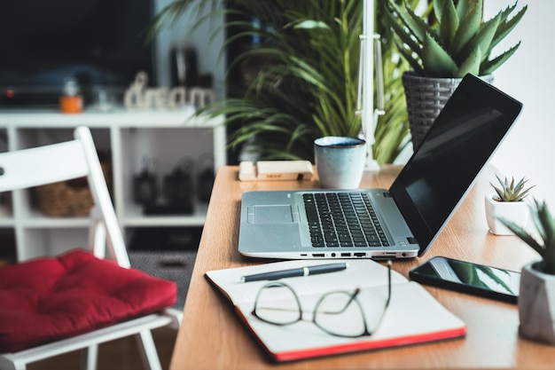 Foto nahaufnahme eines holzschreibtisches mit laptop-planer, handy-brille auf dem arbeitstisch