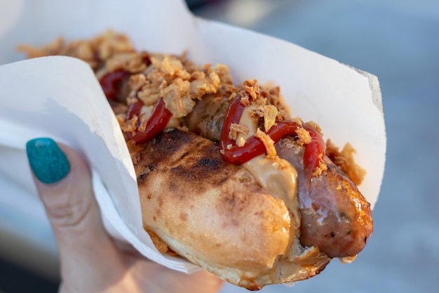 Nahaufnahme eines Hotdogs in einer Papierserviette mit Soße im Freien Selektiver Fokus Street Food