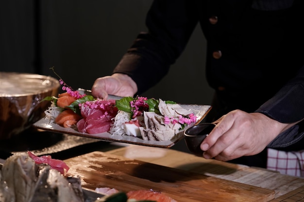 Nahaufnahme eines japanischen Kochs, der sich darauf vorbereitet, japanisches Essen zu kochen Machen Sie Sushi in einem traditionellen japanischen Restaurant auf einem Schneidebrett