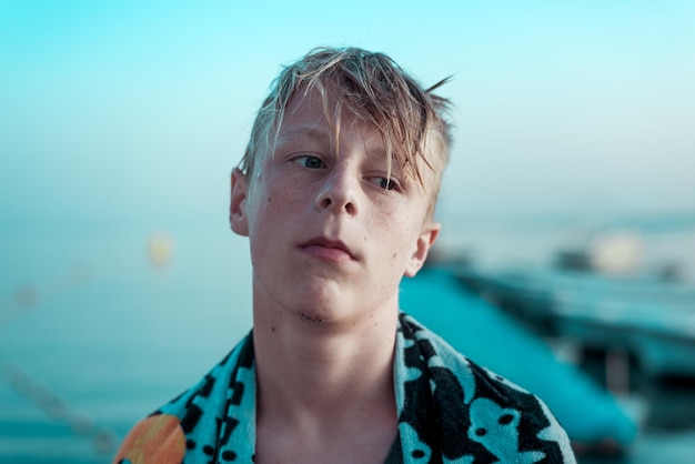 Nahaufnahme eines Jungen, der am Strand gegen den Himmel steht und wegblickt