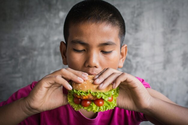 Nahaufnahme eines Jungen, der Burger gegen die Wand isst