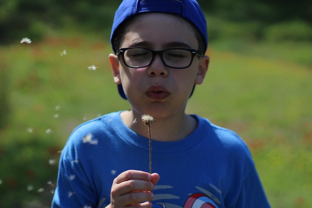 Nahaufnahme eines Jungen, der Löwenzahn bläst