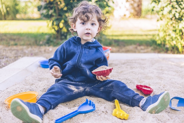 Nahaufnahme eines Jungen, der tagsüber auf dem Spielplatz mit Sand spielt