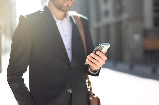 Nahaufnahme eines jungen Geschäftsmannes, der eine Smartphone-Hand hält und verwendet, die eine SMS-Nachricht auf dem Bildschirm hält