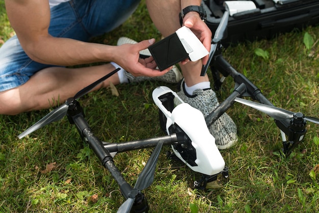 Nahaufnahme eines jungen Ingenieurs, der die Batterie einer Uav-Drohne mit einem Handwerkzeug im Park überprüft