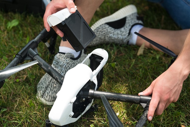 Nahaufnahme eines jungen Ingenieurs, der die Batterie einer Uav-Drohne mit einem Handwerkzeug im Park überprüft