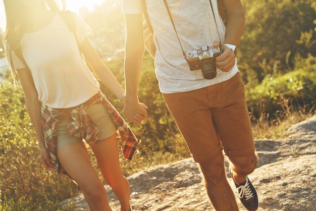 Nahaufnahme eines jungen Liebespaares in Freizeitkleidung, das Händchen hält, während es im Freien spazieren geht