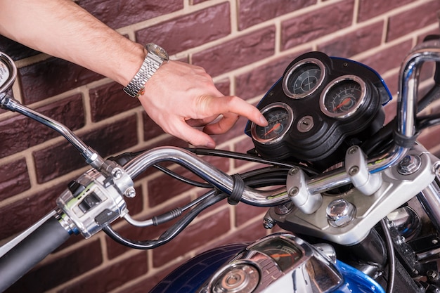 Nahaufnahme eines jungen Mannes, der die Messuhren auf der Motorradkonsole genau untersucht