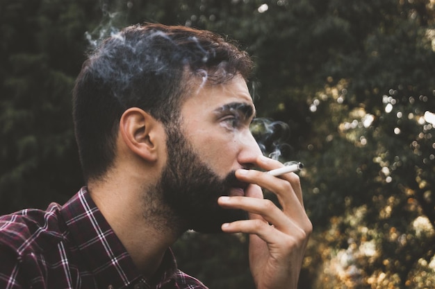 Nahaufnahme eines jungen Mannes, der im Freien raucht