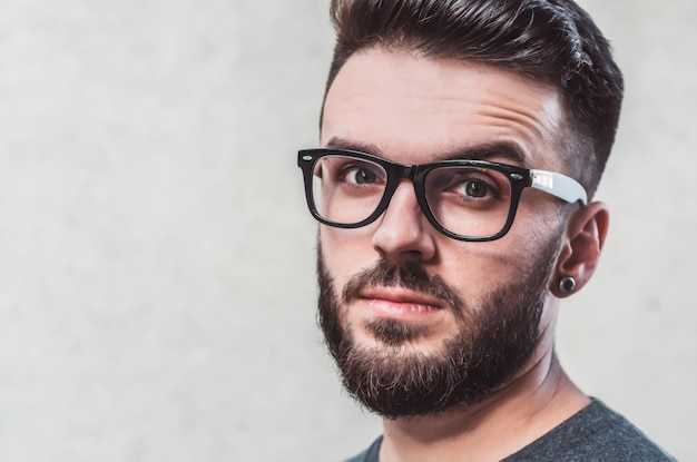 Foto nahaufnahme eines jungen mannes mit brille an der wand