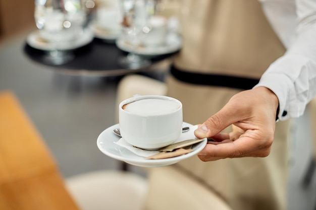 Nahaufnahme eines Kellners, der Kaffee in einem Café serviert