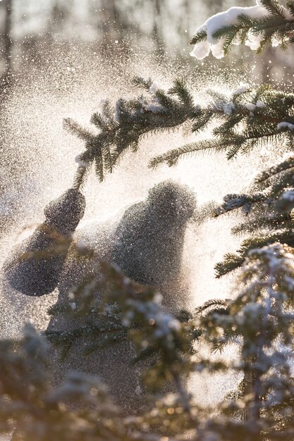 Nahaufnahme eines kleinen jungen, der einen ast mit schnee zieht und schnee fällt auf ihn