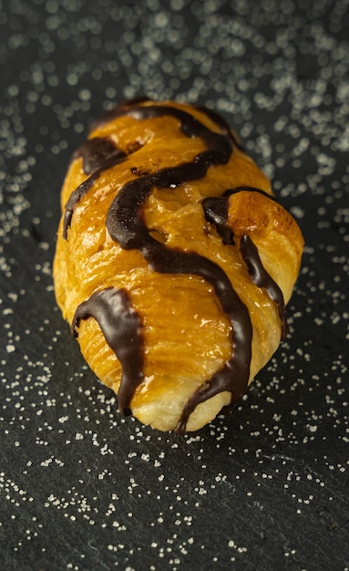 Nahaufnahme eines köstlichen Croissants mit Schokolade auf einem dunklen Hintergrund