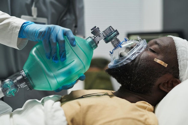 Nahaufnahme eines kranken Mannes, der mit Hilfe einer Sauerstoffmaske atmet, die von einer Krankenschwester gehalten wird