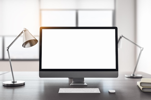 Nahaufnahme eines kreativen Designer-Desktops mit leerem weißen Computerbildschirm auf verschwommenem Hintergrund im Büroinnenraum. 3D-Rendering-Attrappe