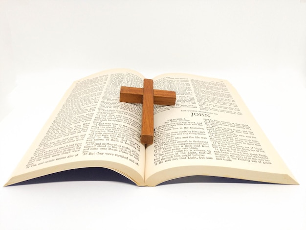 Nahaufnahme eines Kreuzes auf einer offenen Bibel vor weißem Hintergrund