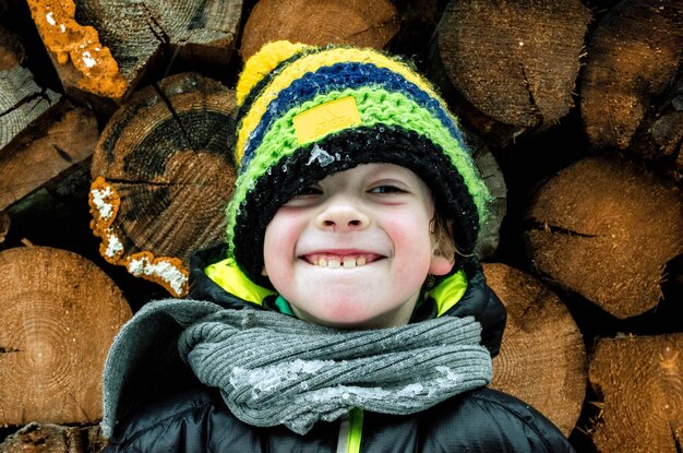 Foto nahaufnahme eines lächelnden jungen, der gegen stämme steht