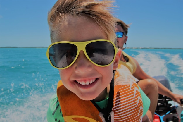Nahaufnahme eines lächelnden Jungen mit Sonnenbrille, der auf einem Boot reist