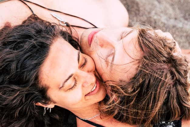 Foto nahaufnahme eines lächelnden mannes und einer frau, die am strand auf dem sand liegen