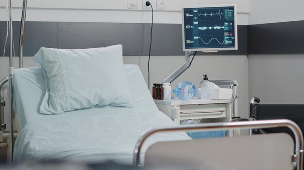 Nahaufnahme eines leeren Krankenhausbettes mit medizinischer Ausrüstung. Notaufnahme mit Reanimationswerkzeugen für das Gesundheitswesen, Herzfrequenzmonitor und Sauerstoffschlauch. Platz für intensivmedizinische Erholung