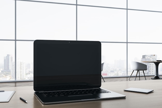 Nahaufnahme eines leeren Notebook-Bildschirms auf einem hölzernen Bürodesktop mit Vorräten auf Panoramafenster und Blick auf die Stadt im Hintergrund Mock-up-3D-Rendering