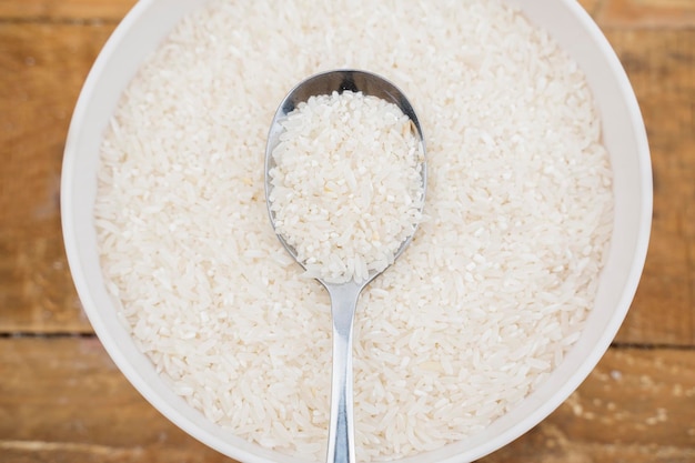 Nahaufnahme eines Löffels weißen Reiskornes auf dem weißen Reiskorn in einer Schüssel