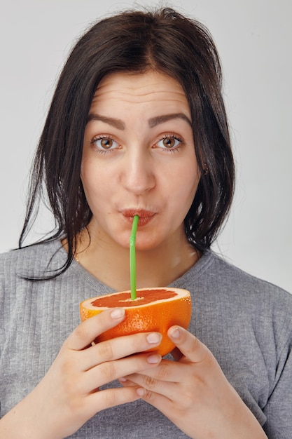 Nahaufnahme eines Mädchens, das einen Saft von der Orangenfrucht trinkt