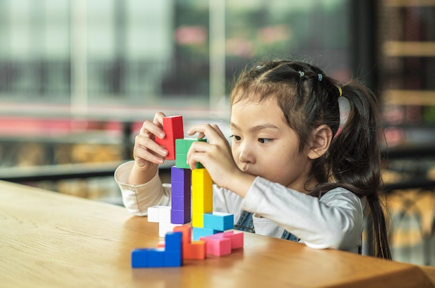 Nahaufnahme eines Mädchens, das mit Spielzeugblöcken auf dem Tisch spielt