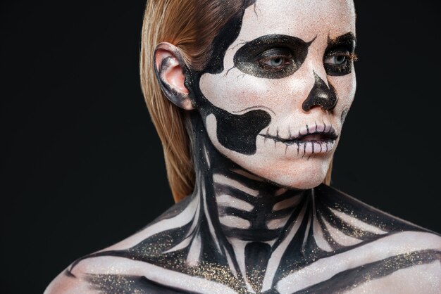 Nahaufnahme eines Mädchens mit schrecklichem Halloween-Make-up auf schwarzem Hintergrund