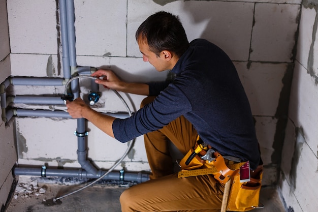 Nahaufnahme eines männlichen Klempners repariert Rohre in der Toilette