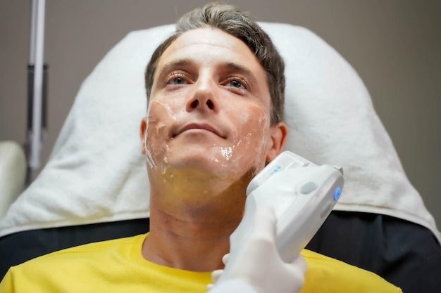 Nahaufnahme eines männlichen Kunden mit Farblichttherapie zur Stimulierung der Gesichtshaut