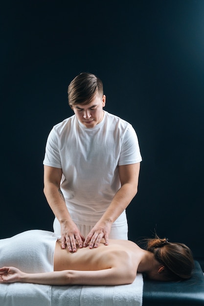 Nahaufnahme eines männlichen Masseurs, der den Rücken der jungen Frau massiert, die auf dem Massagetisch liegt?