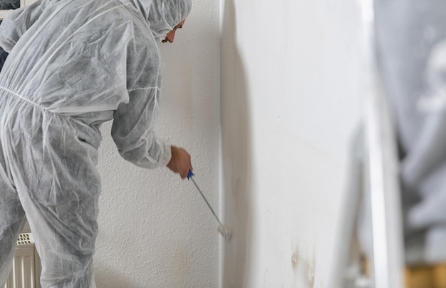 Nahaufnahme eines Malers, der mit einer Farbrolle arbeitet, um den Raum in weißer Farbe zu streichen. Konzeptbild zum Selbermachen