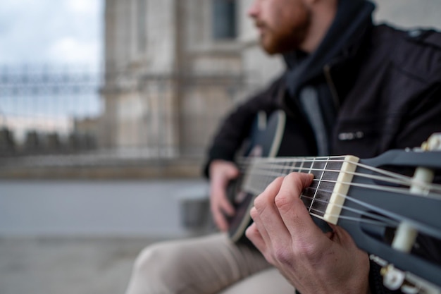 Nahaufnahme eines Mannes, der auf der Straße sitzt und mit den Händen Gitarre spielt Musikkonzept