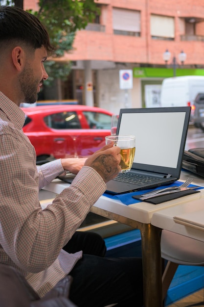 Nahaufnahme eines Mannes, der aus der Ferne mit einem Laptop von einem Restaurant aus arbeitet