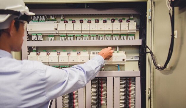 Nahaufnahme eines Mannes, der das elektrische Schaltbrett untersucht