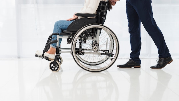 Foto nahaufnahme eines mannes, der die frau sitzt auf rollstuhl drückt