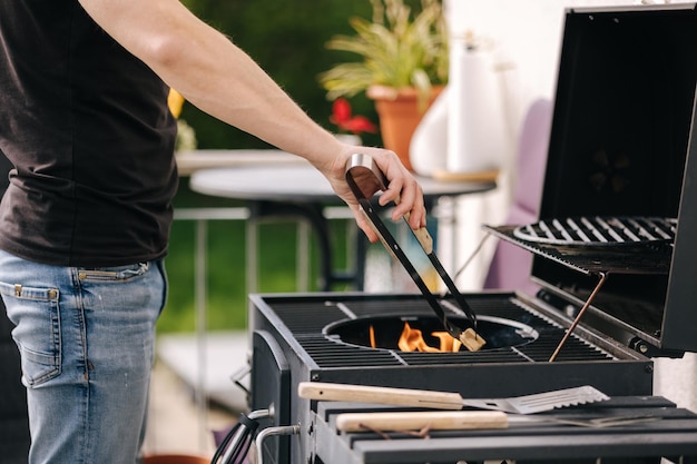 Foto nahaufnahme eines mannes, der ein feuer macht und den prozess beim grillen im freien steuert