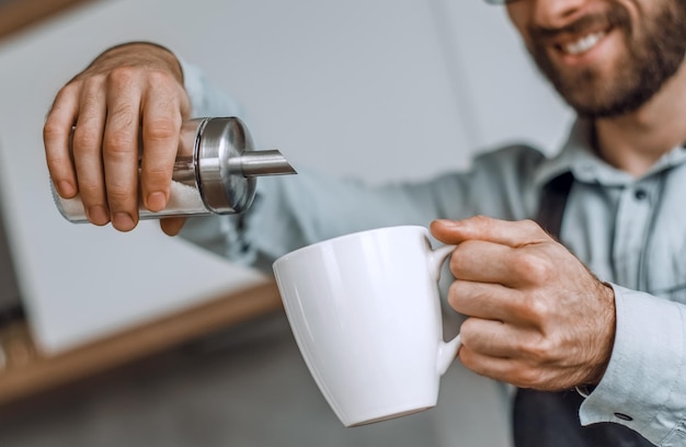 Nahaufnahme eines Mannes, der einer Tasse Tee Zucker hinzufügt