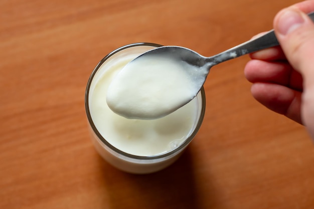 Nahaufnahme eines Mannes, der Joghurt isst Geschmackhafte, nützliche Milchprodukte für einen gesunden Magen