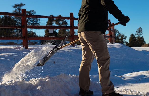 Nahaufnahme eines Mannes, der mitten im Winter Schnee von der Straße nimmt