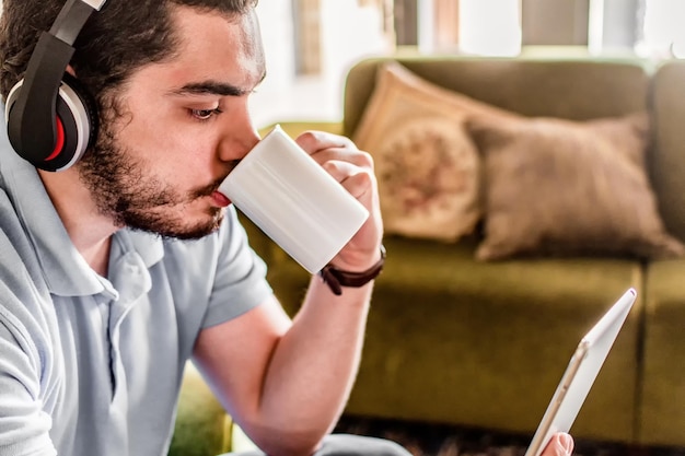 Nahaufnahme eines Mannes, der zu Hause Kaffee trinkt und ein E-Buch liest