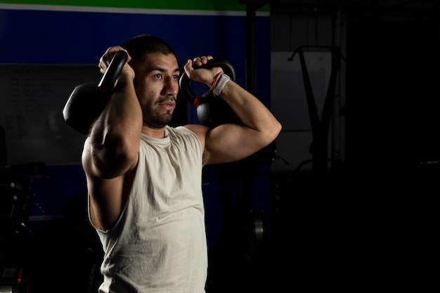 Nahaufnahme eines Mannes mit 2 Kettlebells, der Armübungen macht