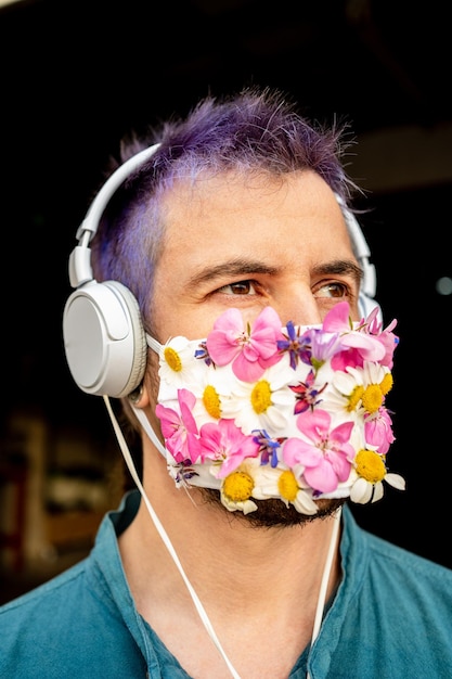 Foto nahaufnahme eines mannes mit blumenmaske und kopfhörern