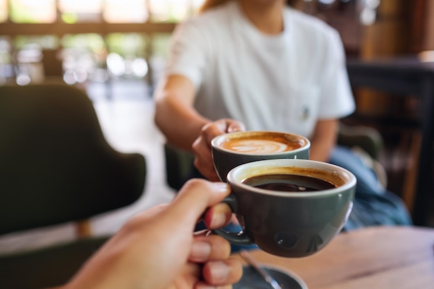 Nahaufnahme eines Mannes und einer Frau, die im Café mit Kaffeetassen klirren